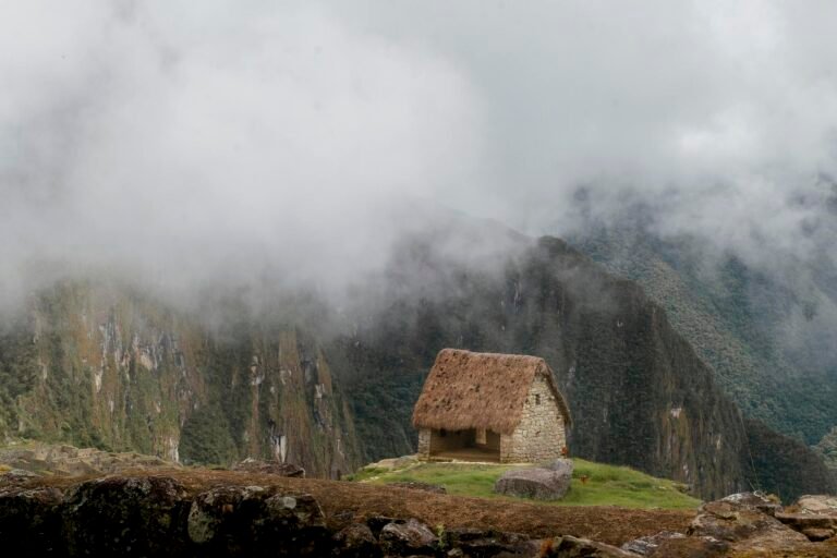 Breathtaking view of a rustic stone hut amidst the misty mountains of Machu Picchu, Peru.